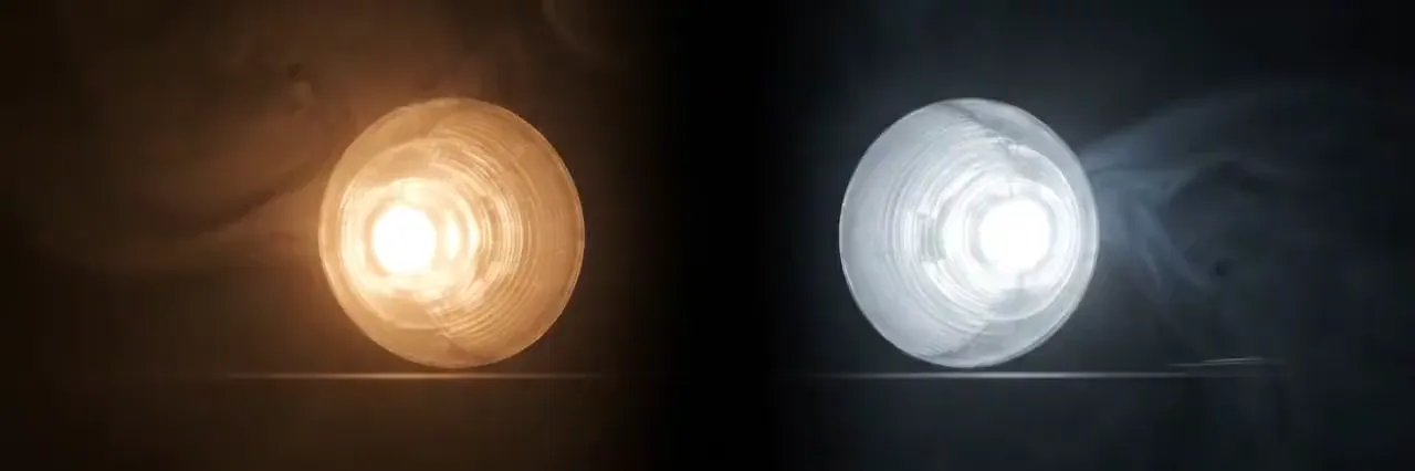 Zwei Lampen im Dunkeln nebeneinander: links eine warm leuchtende Glühlampe, rechts eine kühl weiße Leuchte.